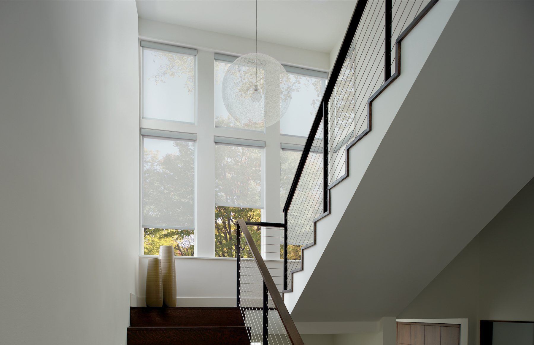 Interior staircase with white walls, dark wood steps, and a large window with sheer blinds.