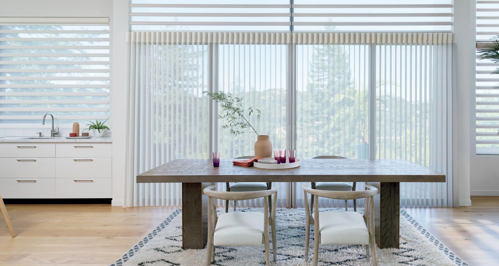 Dining room with a wooden table, chairs, rug, and window blinds.