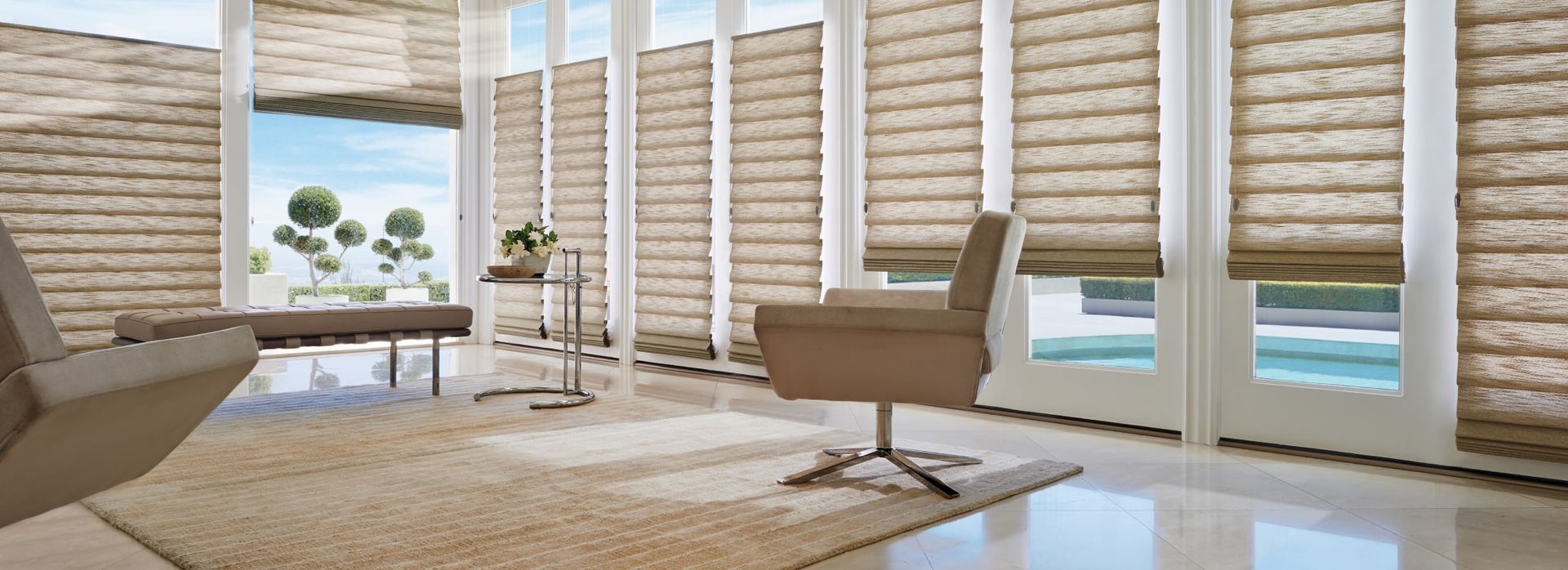 A bright living room with large windows, light brown blinds, and modern furniture.