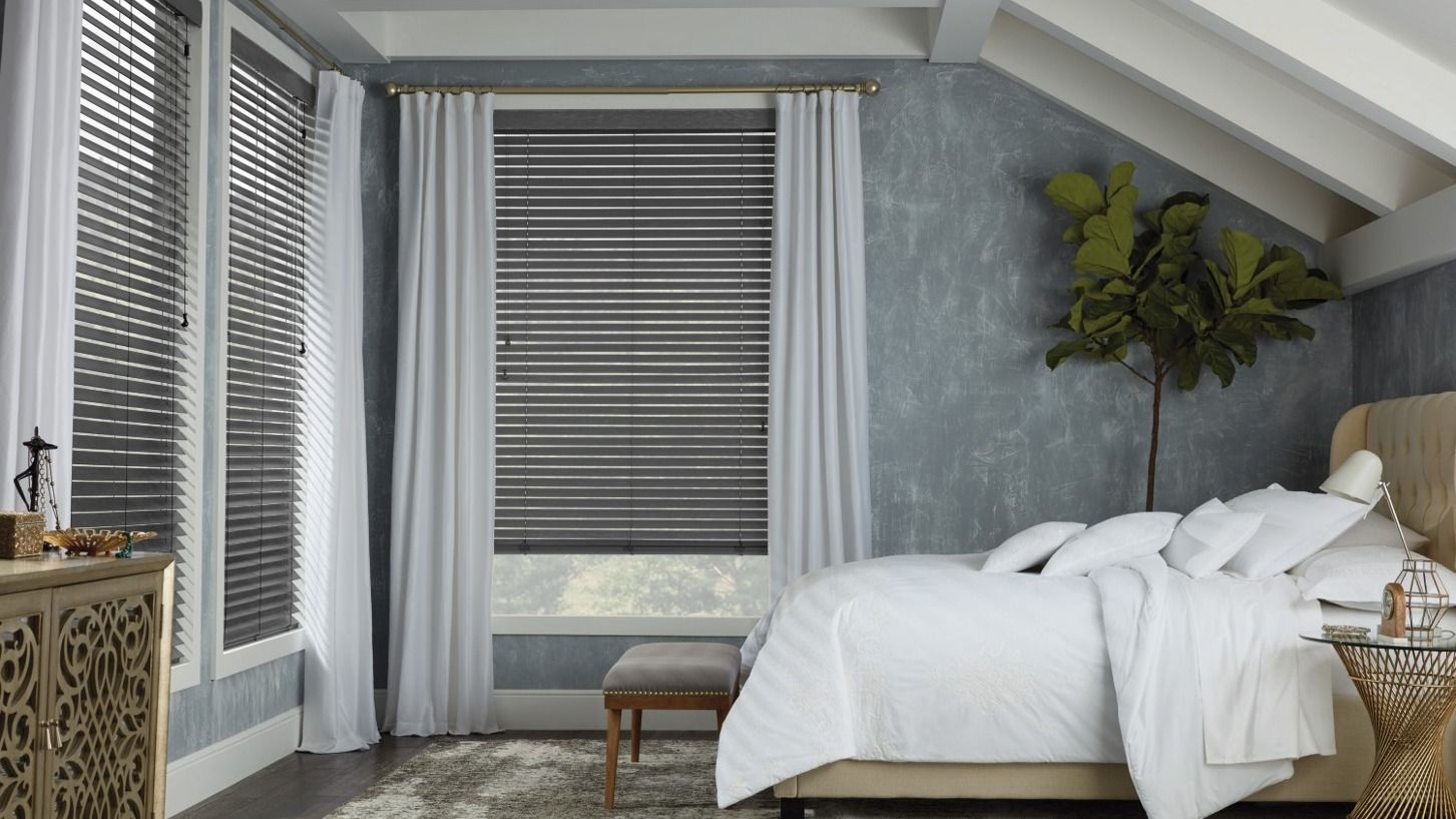 Bedroom with bed, blinds, curtains, textured blue wall, and decorative furniture.
