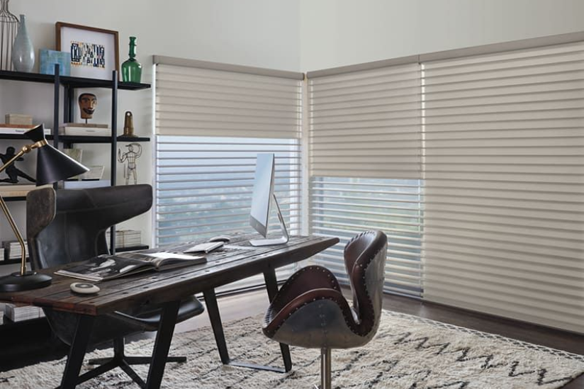Office with desk, chair, and large windows with blinds; neutral tones.