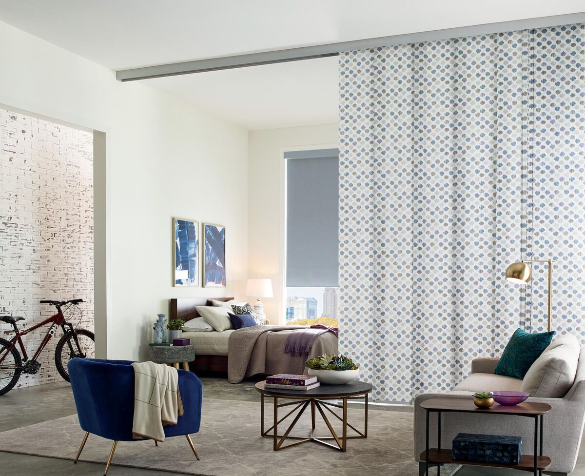 Modern living room with a patterned room divider, separating a bedroom.