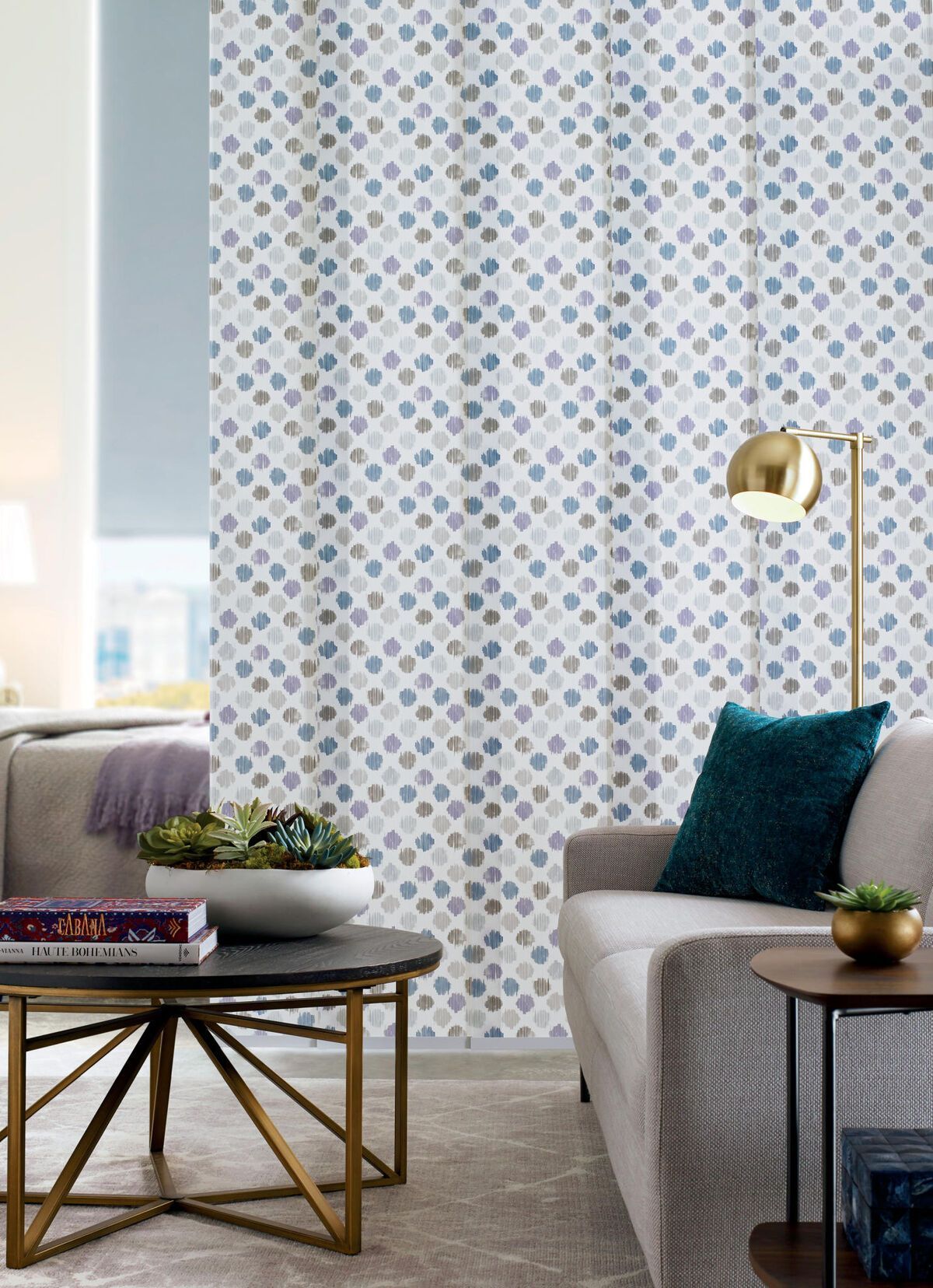 Living room with patterned curtain, sofa, coffee table, and gold accents.