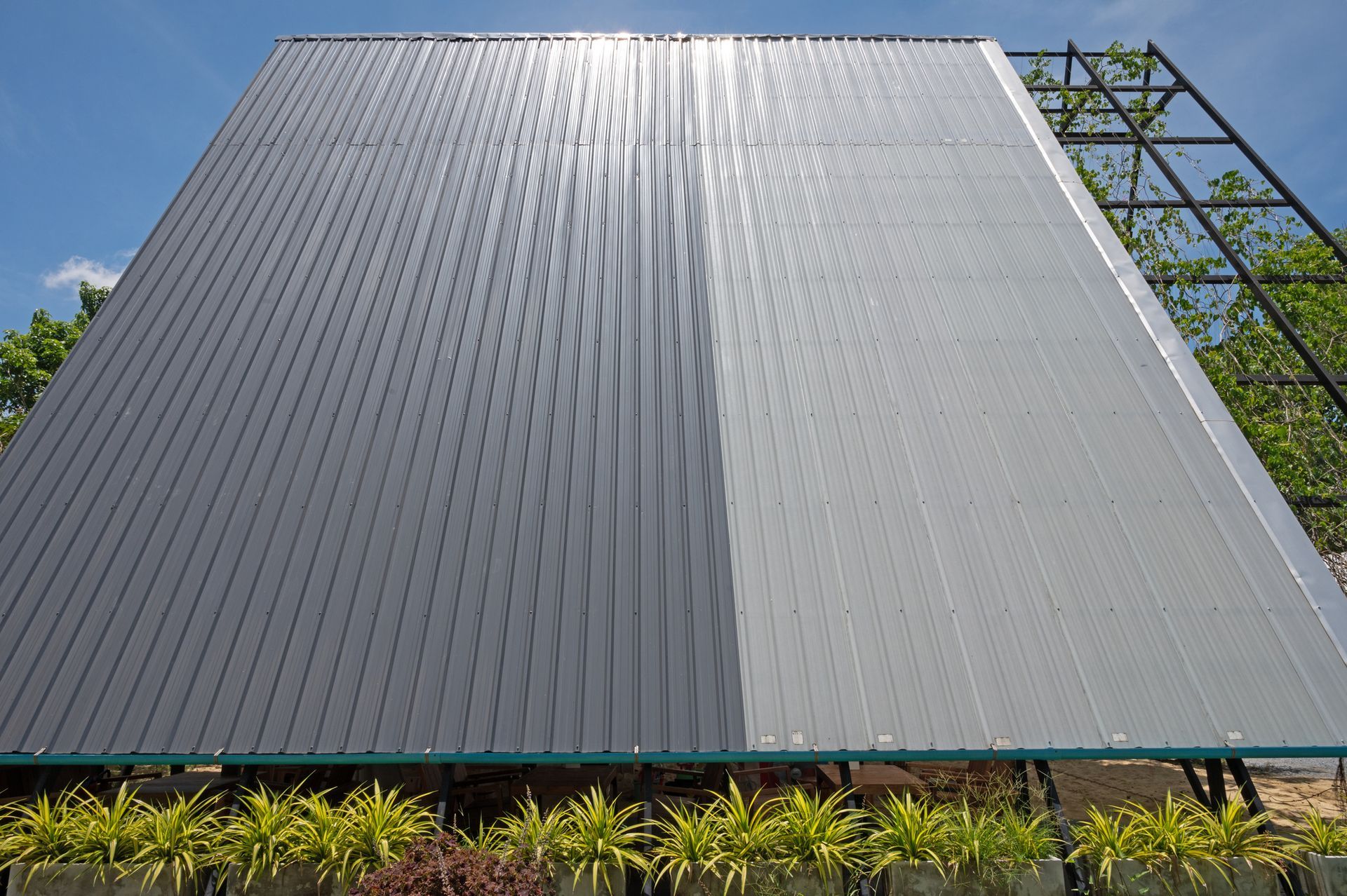 The roof of a building is being painted gray and white