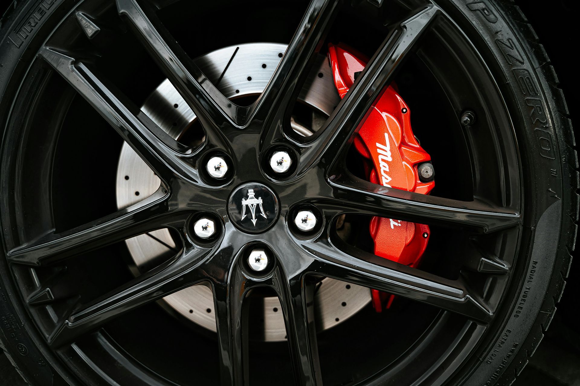 A close up of a maserati wheel with a red brake caliper.