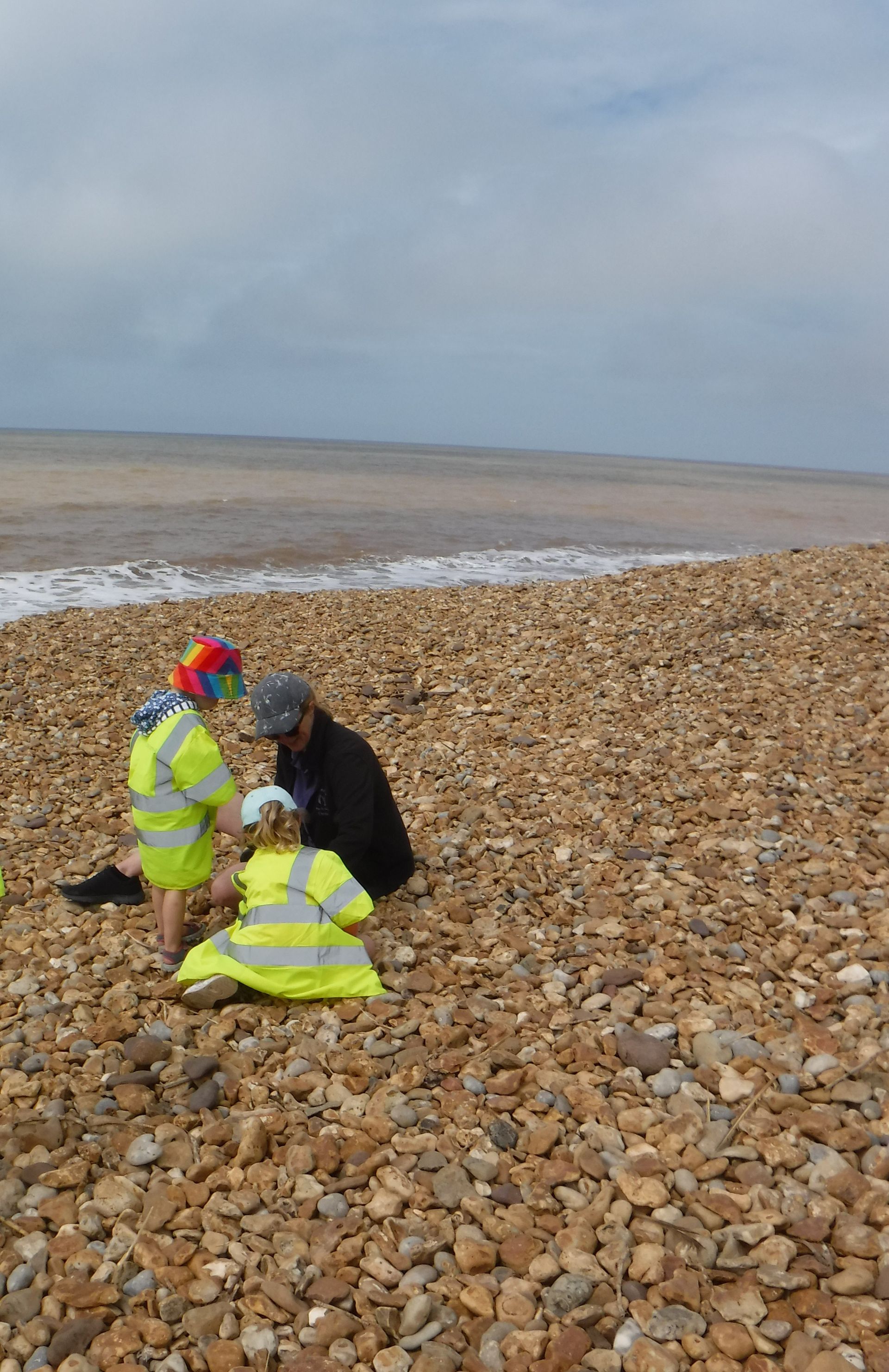 Two people are sitting on a rocky beach near the ocean.