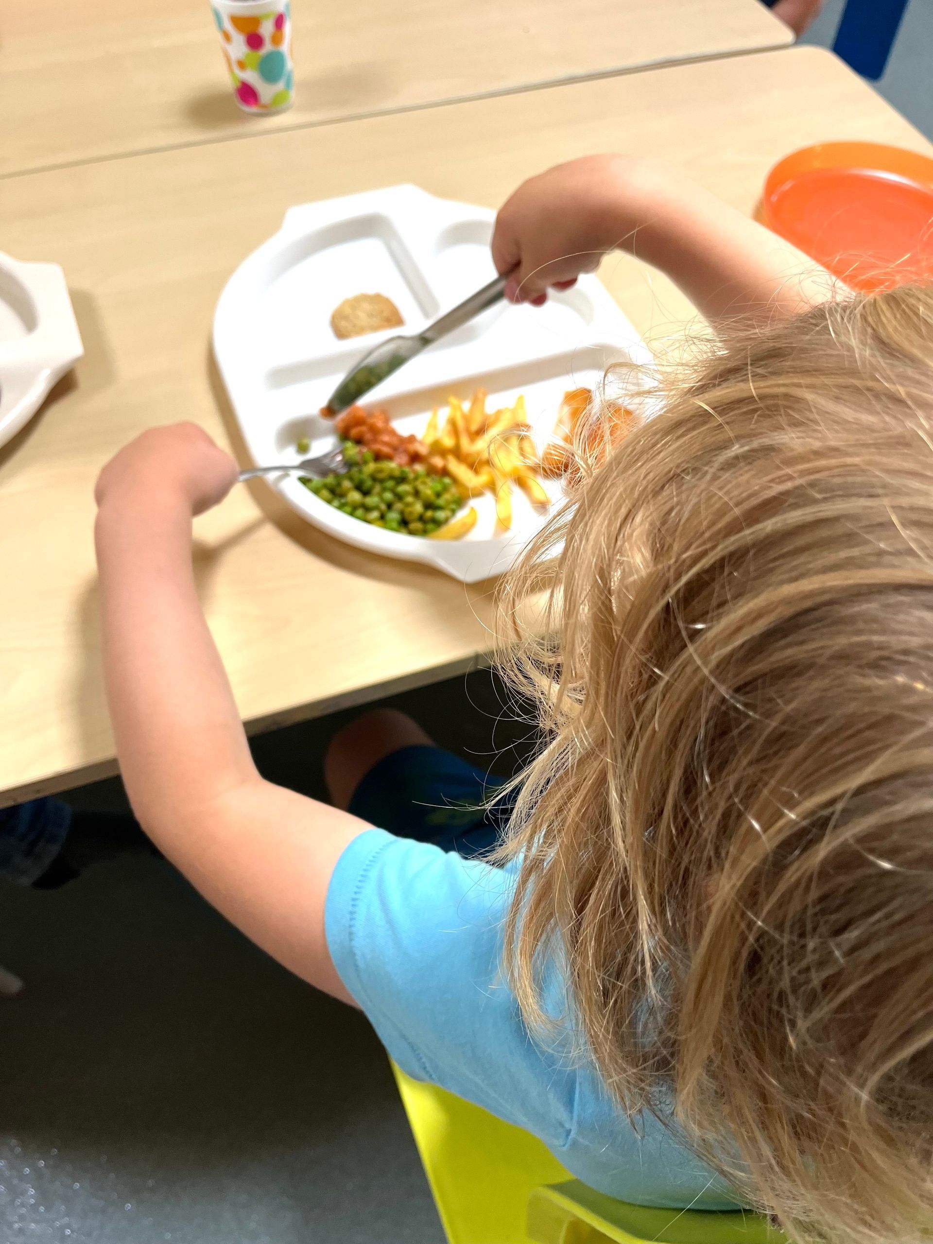 A child is sitting at a table eating a plate of food