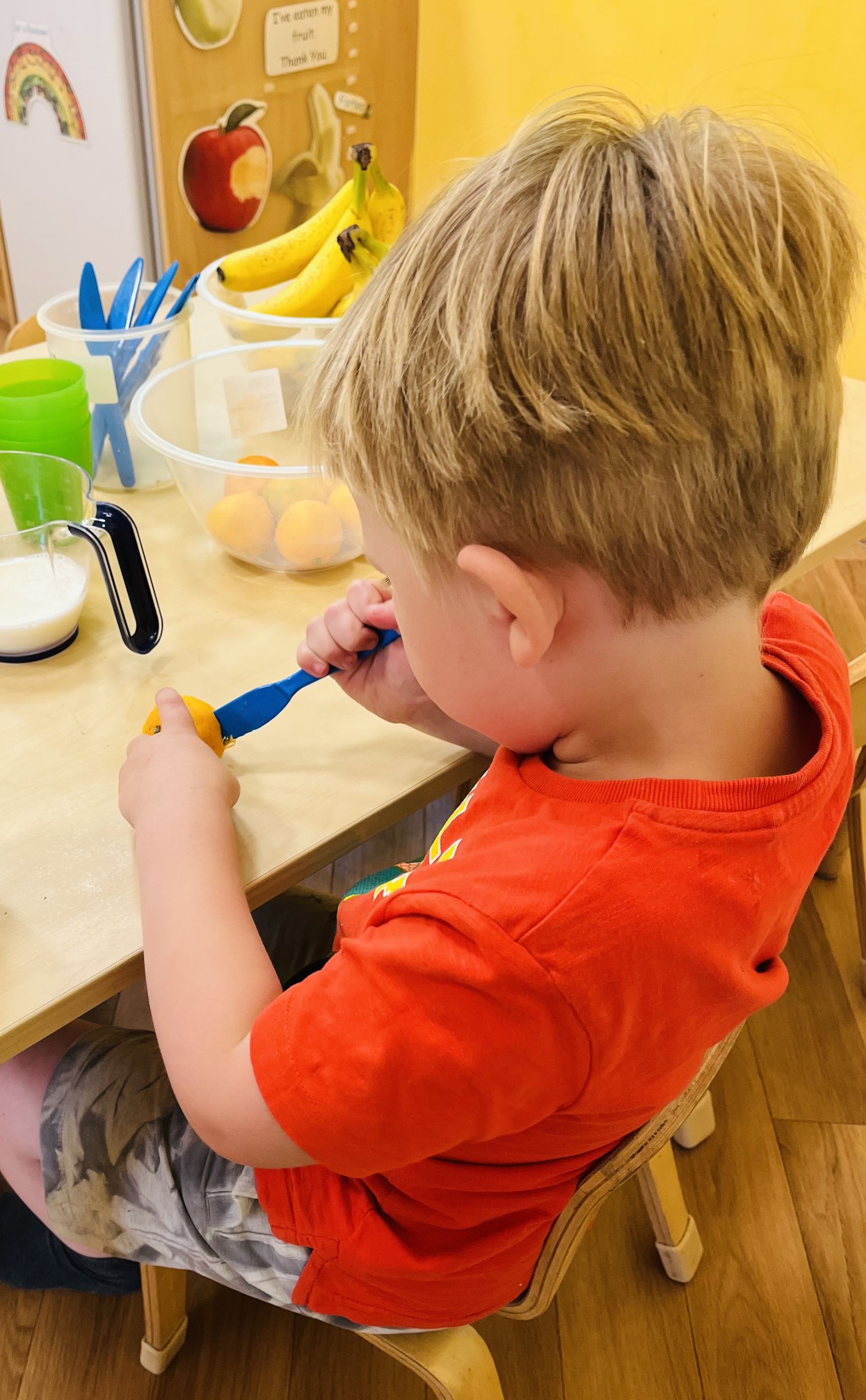 A young boy is brushing his teeth while sitting at a table.