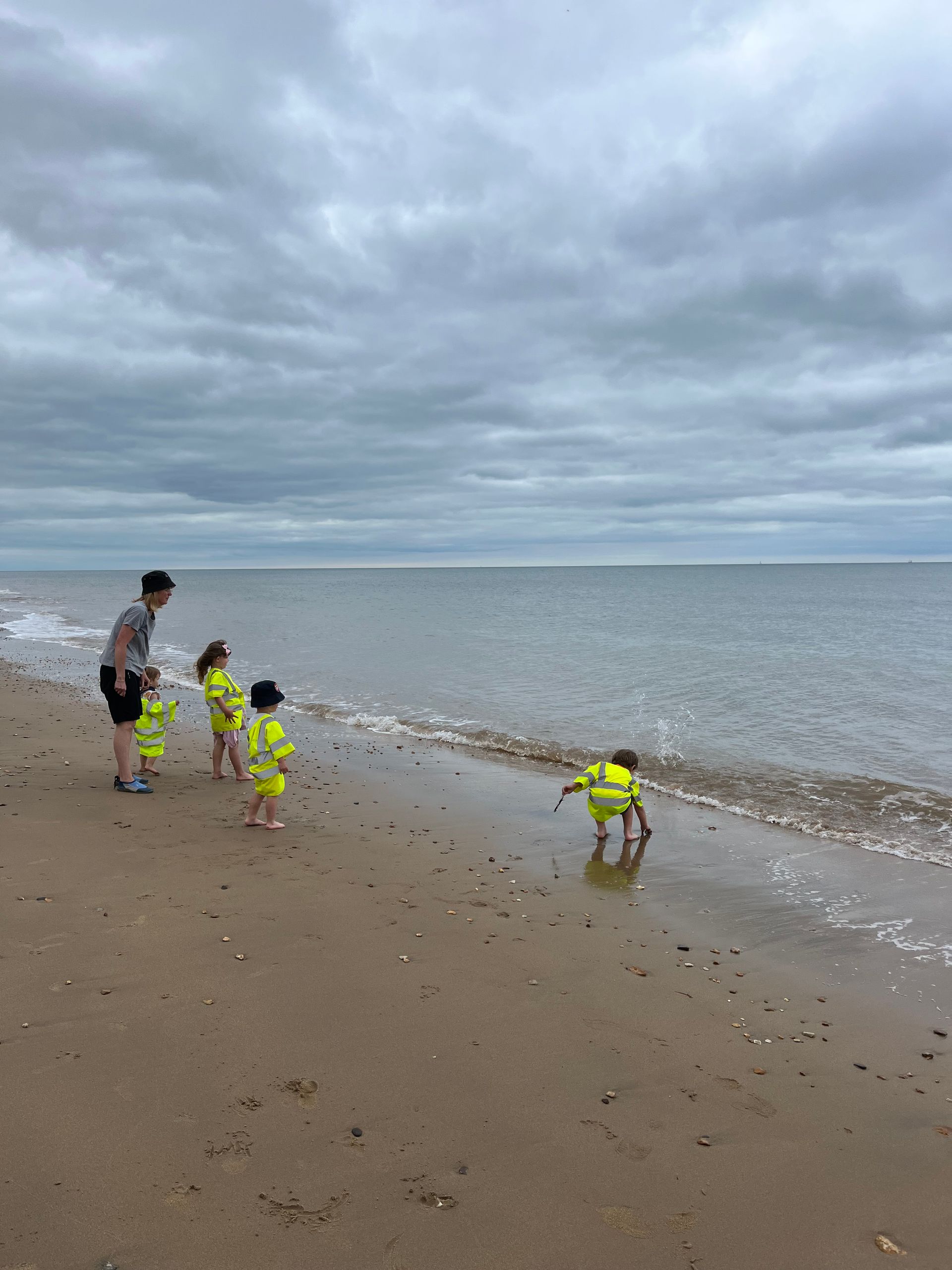 A man and three children are standing on a beach near the ocean.