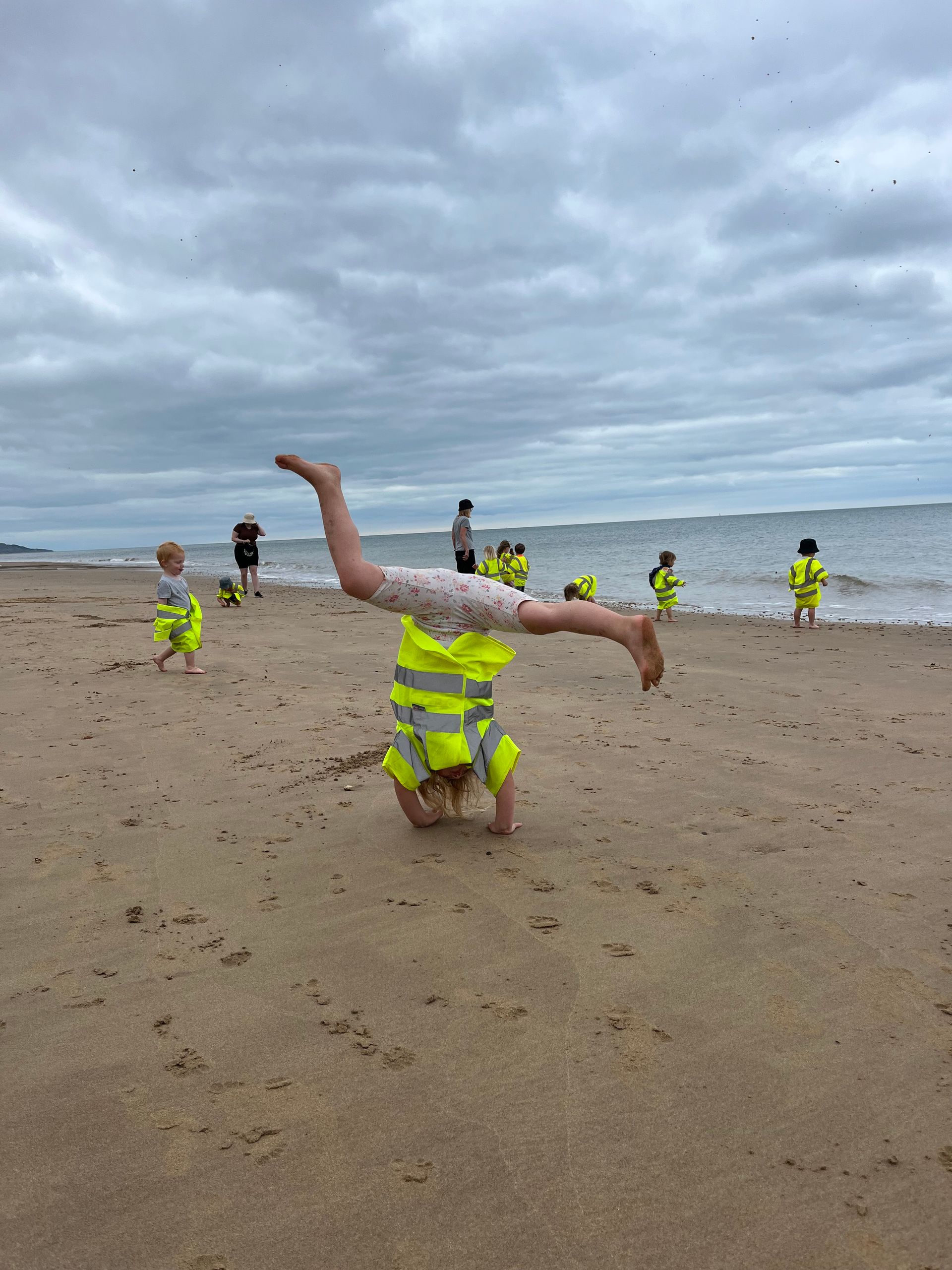 A young girl is doing a handstand on the beach.