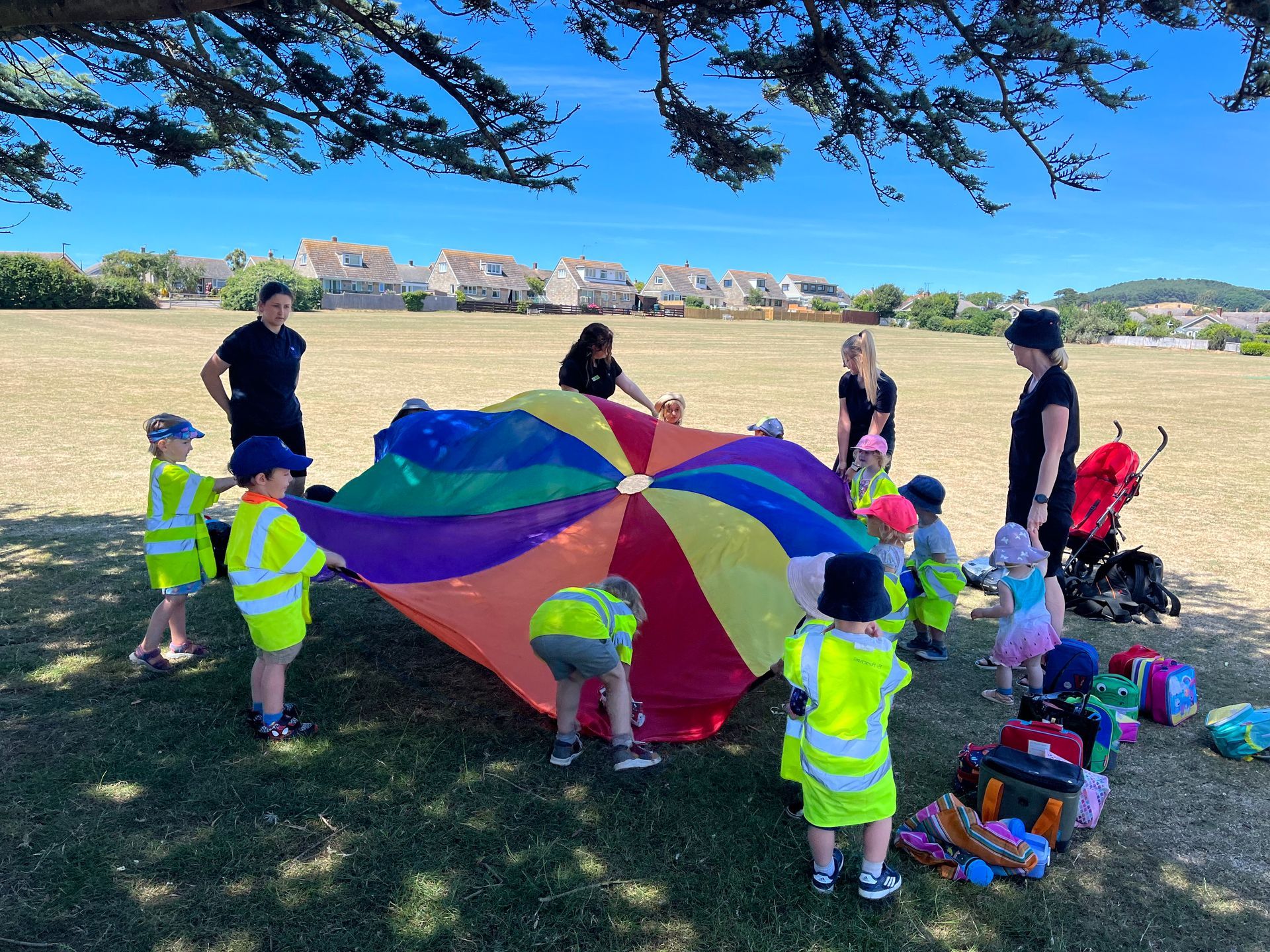 A group of children are playing with a colorful parachute in a park.
