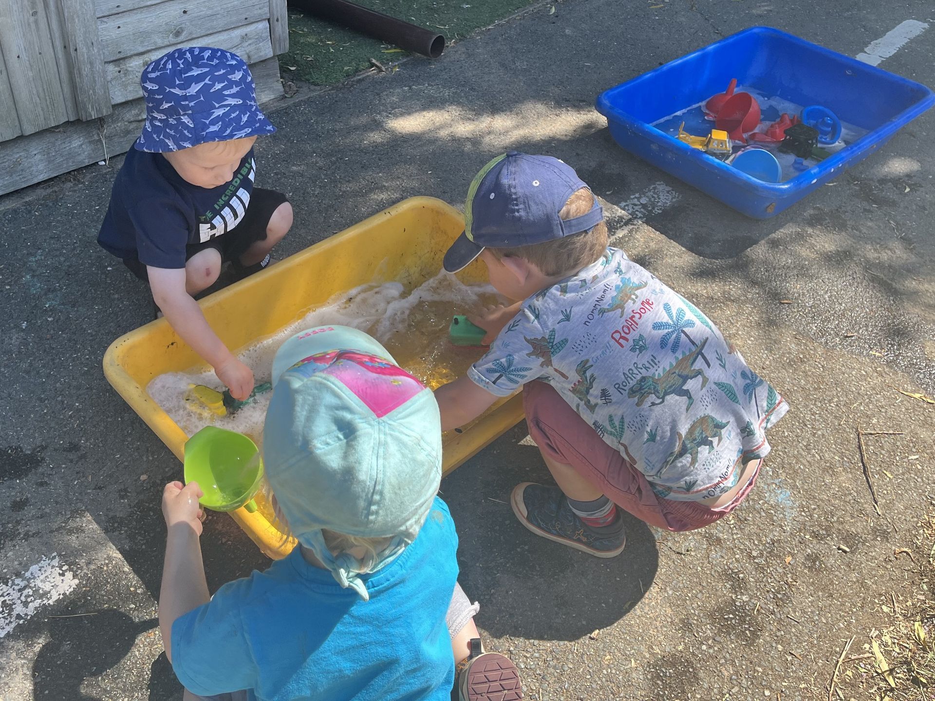 Three young children are playing in a sandbox.