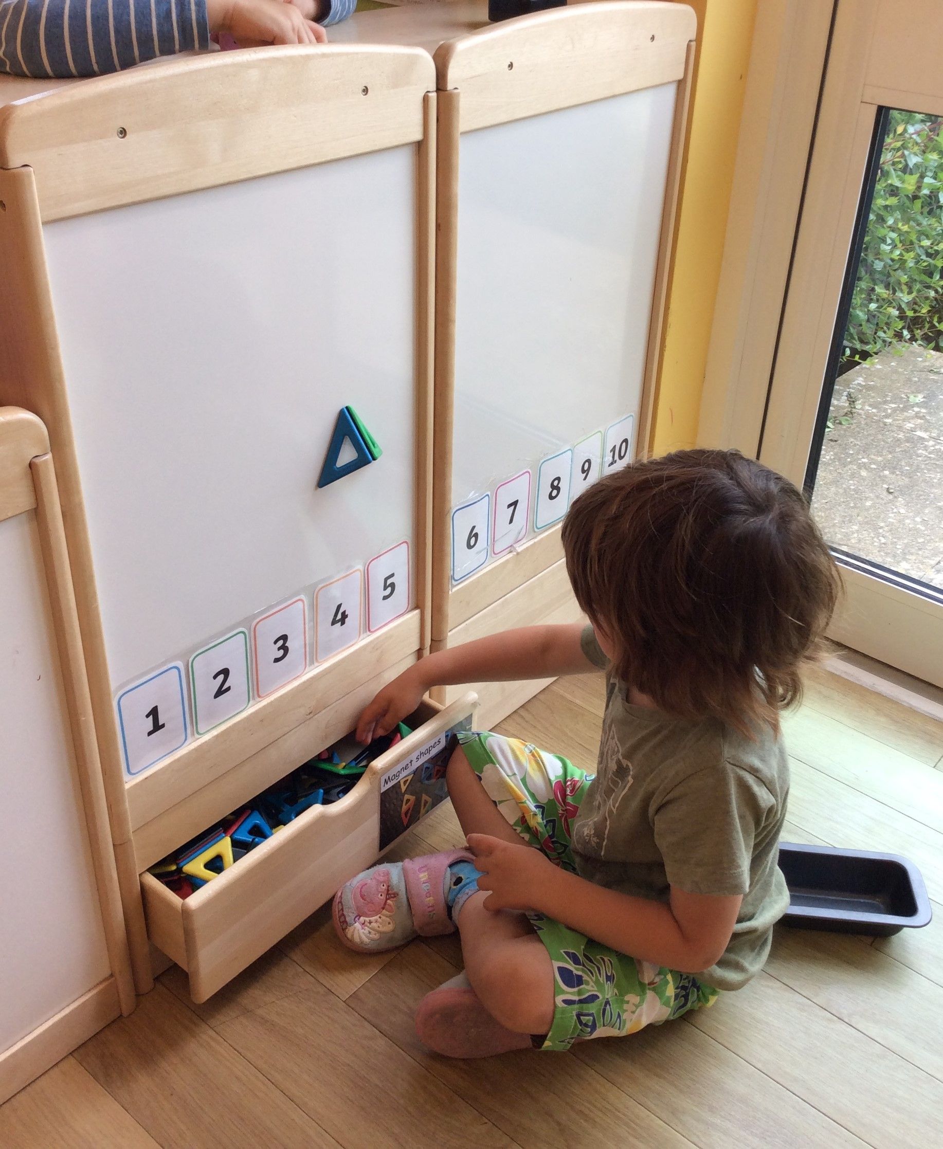 A young boy is sitting on the floor playing with numbers and letters.