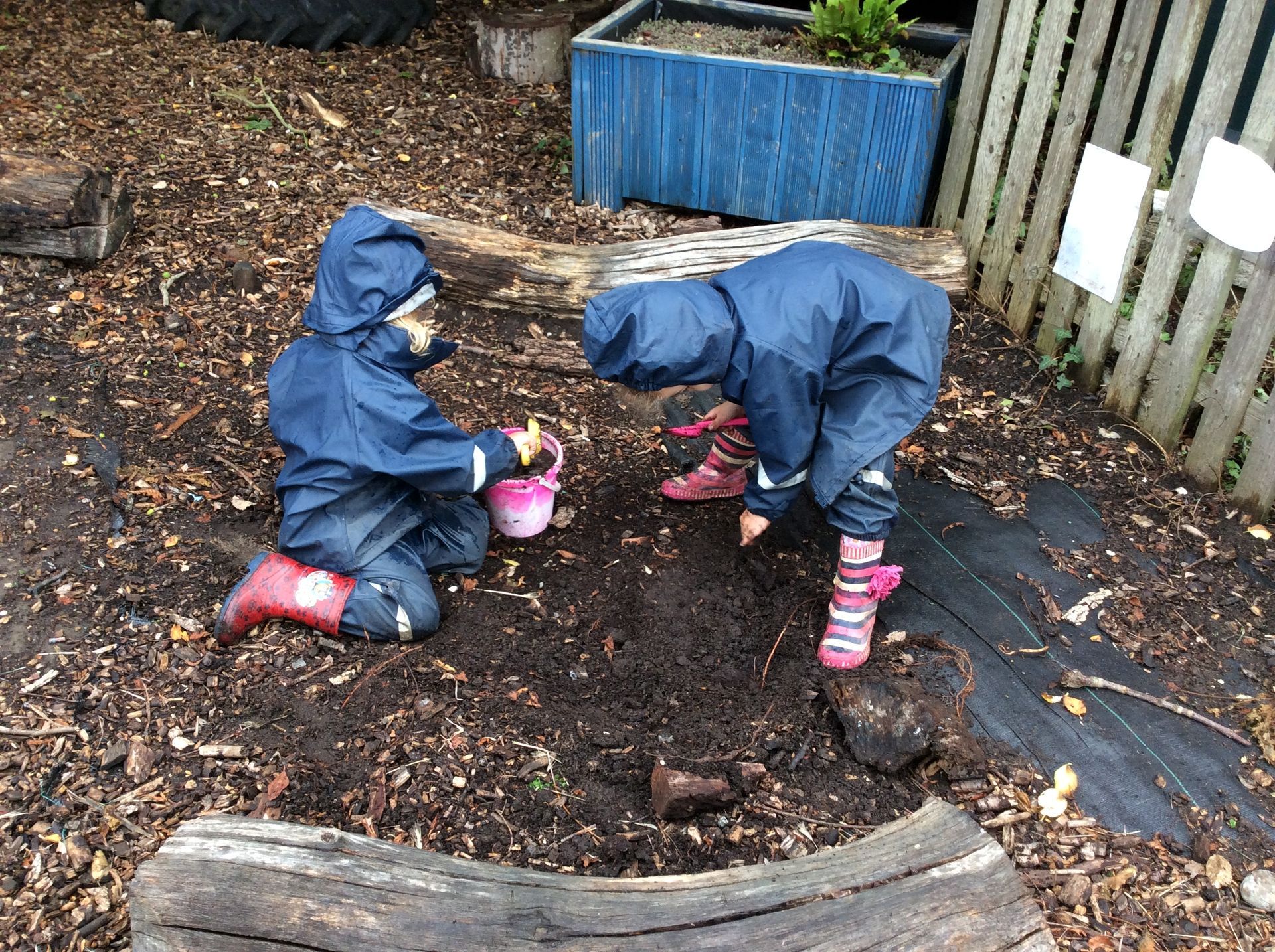 Two children are playing in the dirt in a playground.