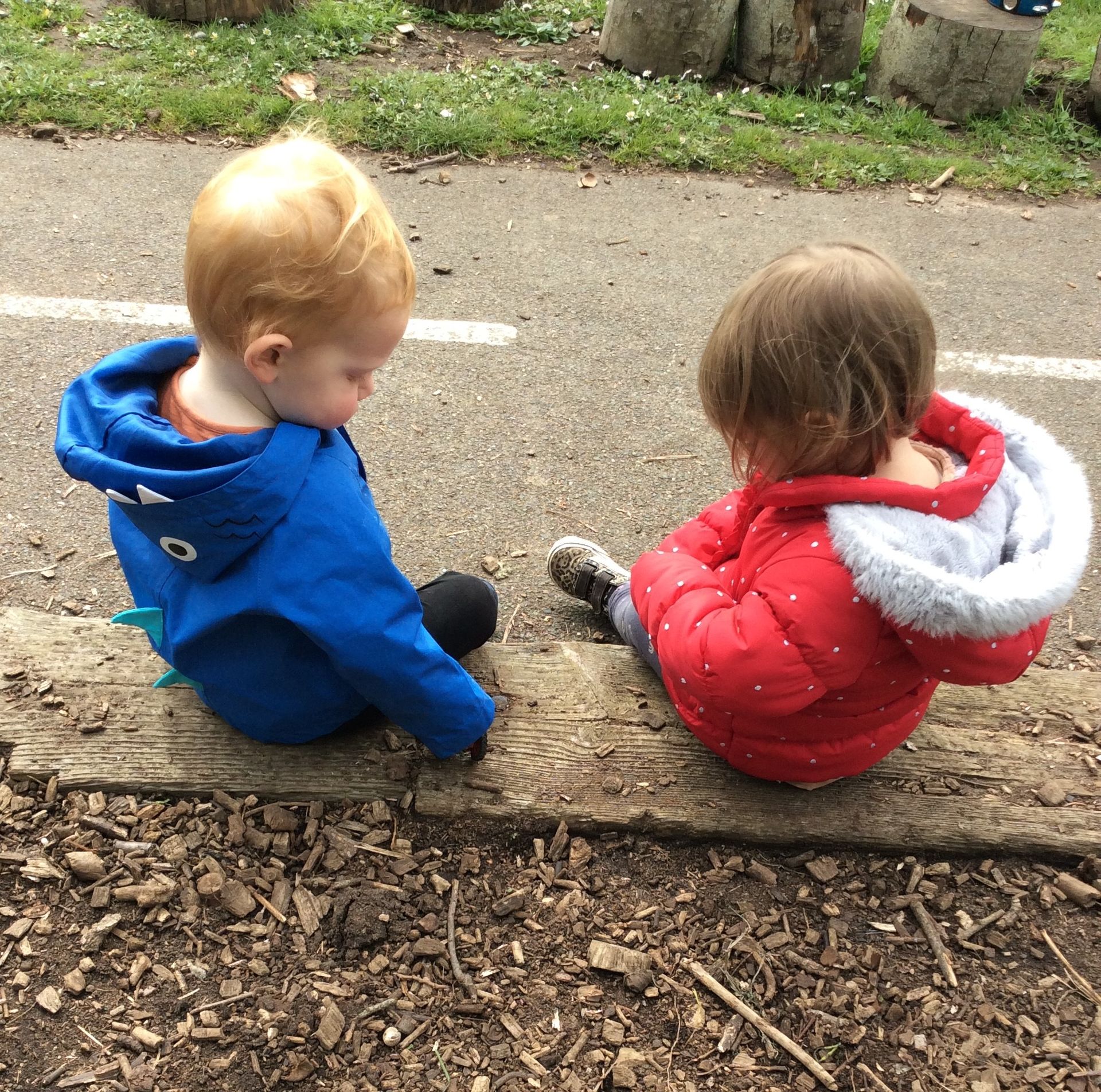 A boy in a blue jacket sits next to a girl in a red jacket