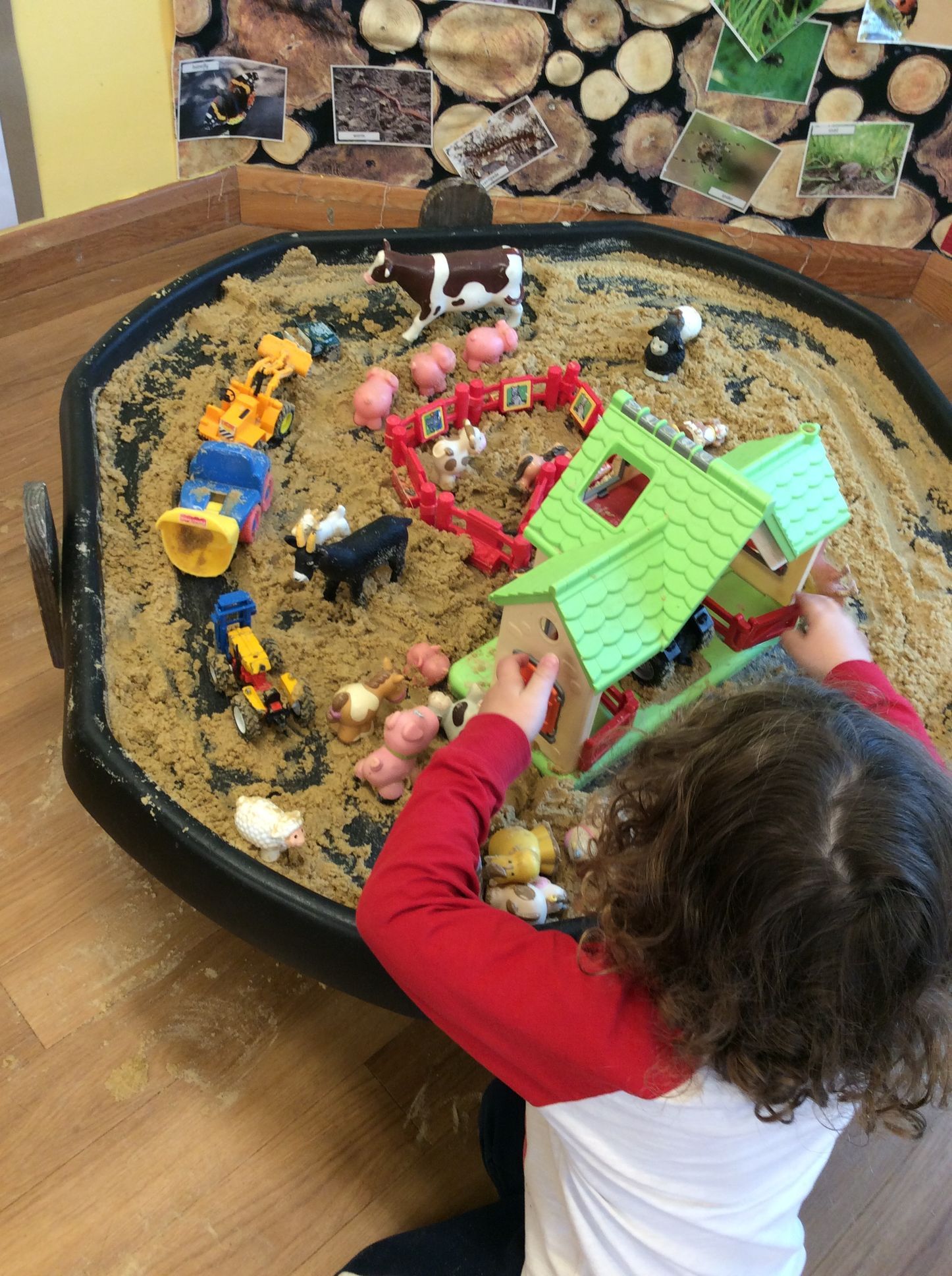 A little girl is playing with toys in a sandbox.
