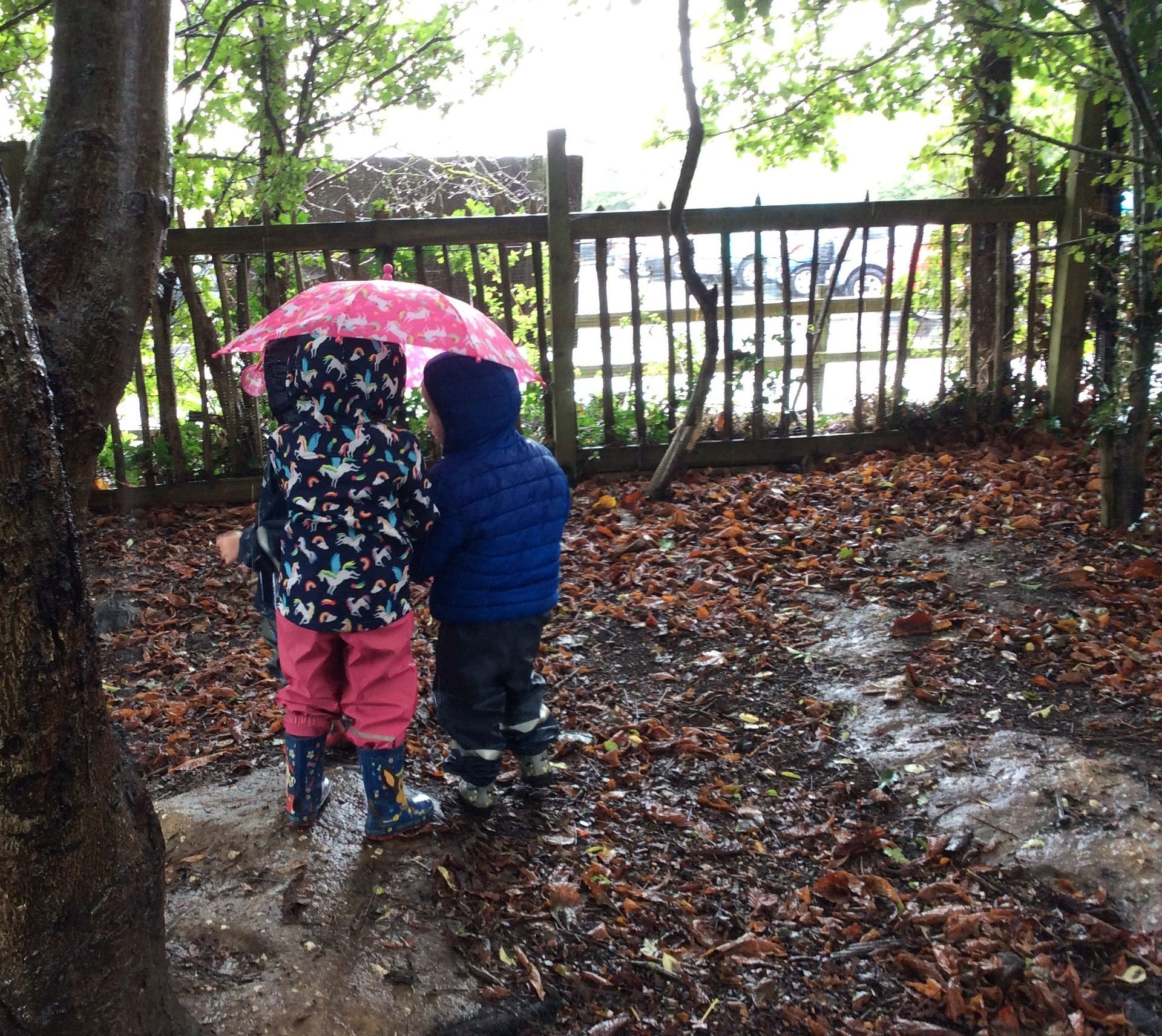Two children holding an umbrella in the rain
