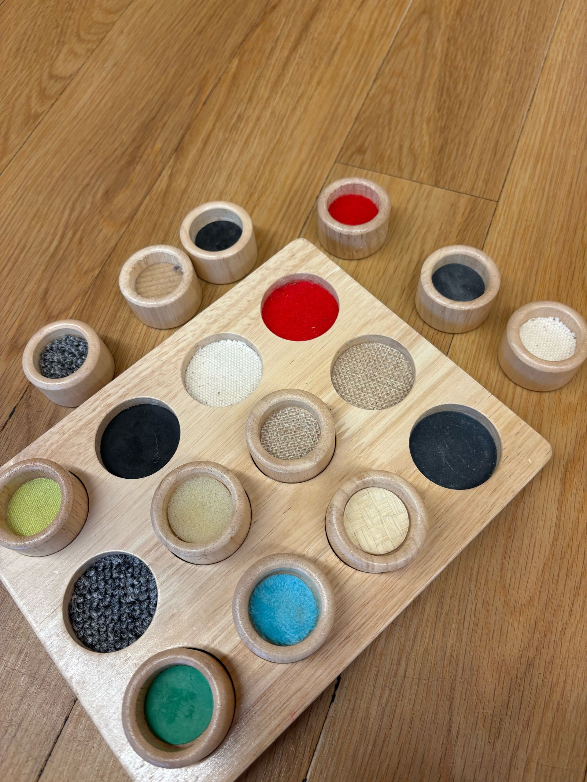 A wooden tray filled with different colored circles on a wooden floor.