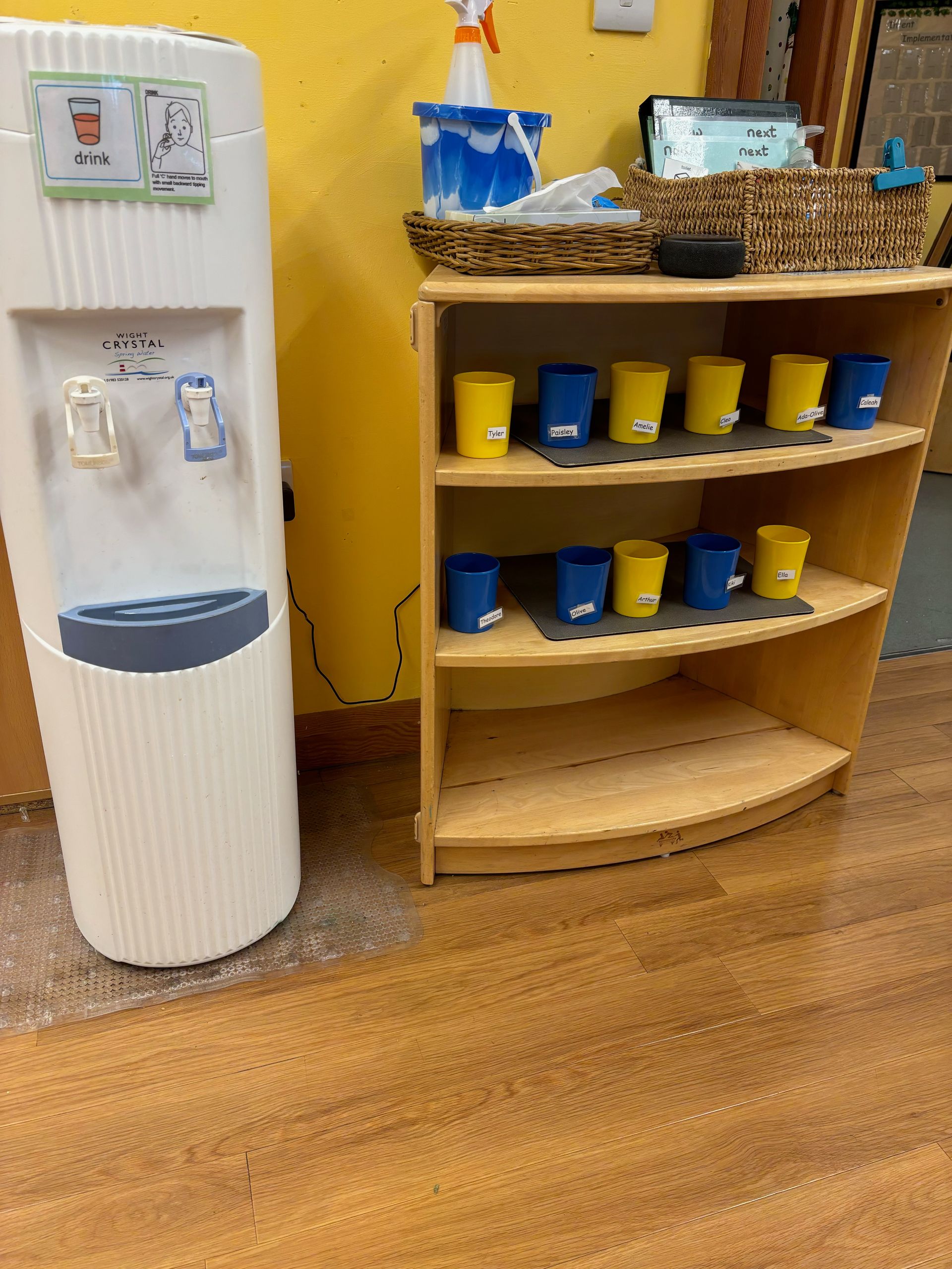 A water dispenser next to a shelf with buckets on it