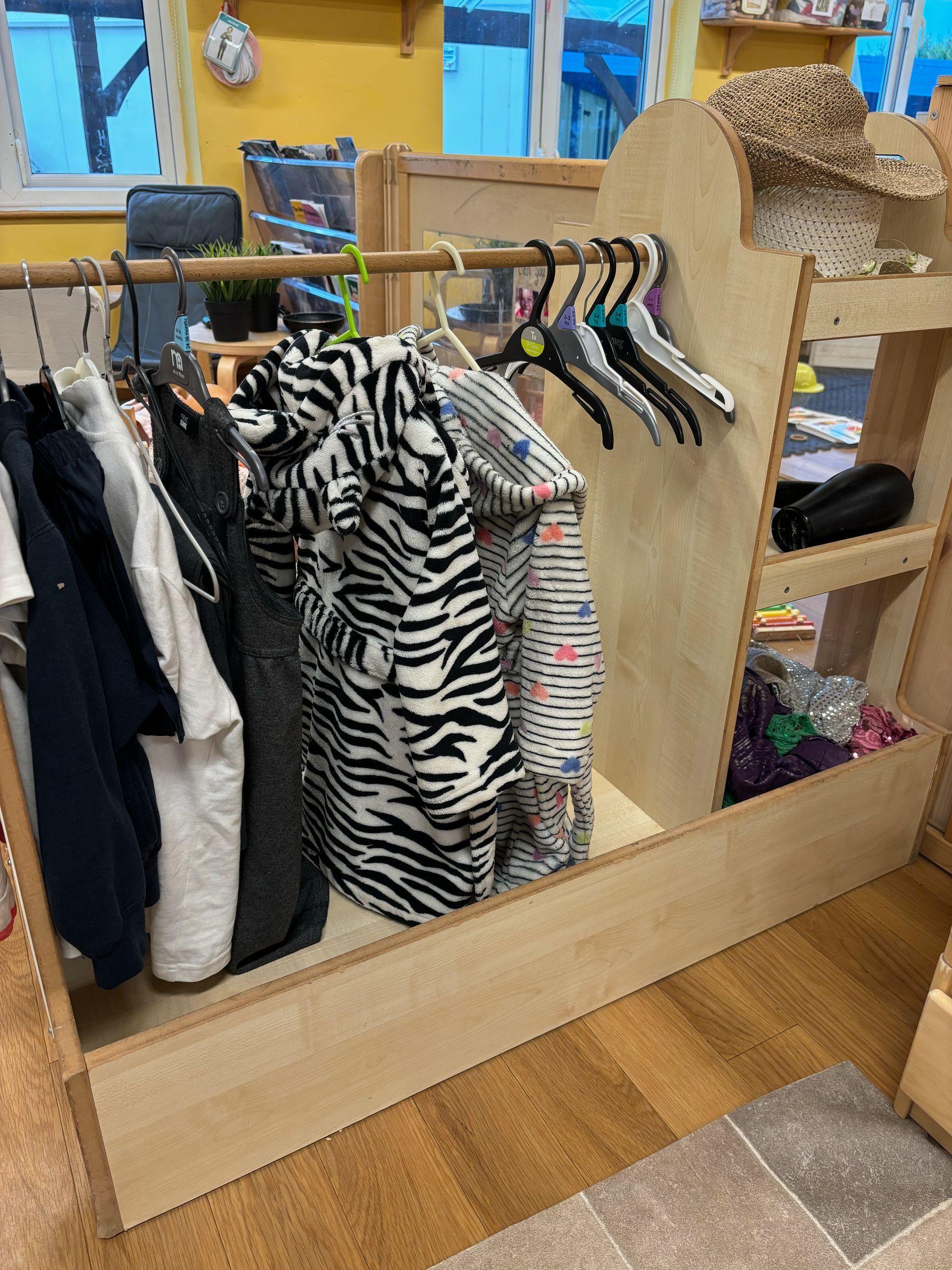 A wooden closet with clothes hanging on a rack.