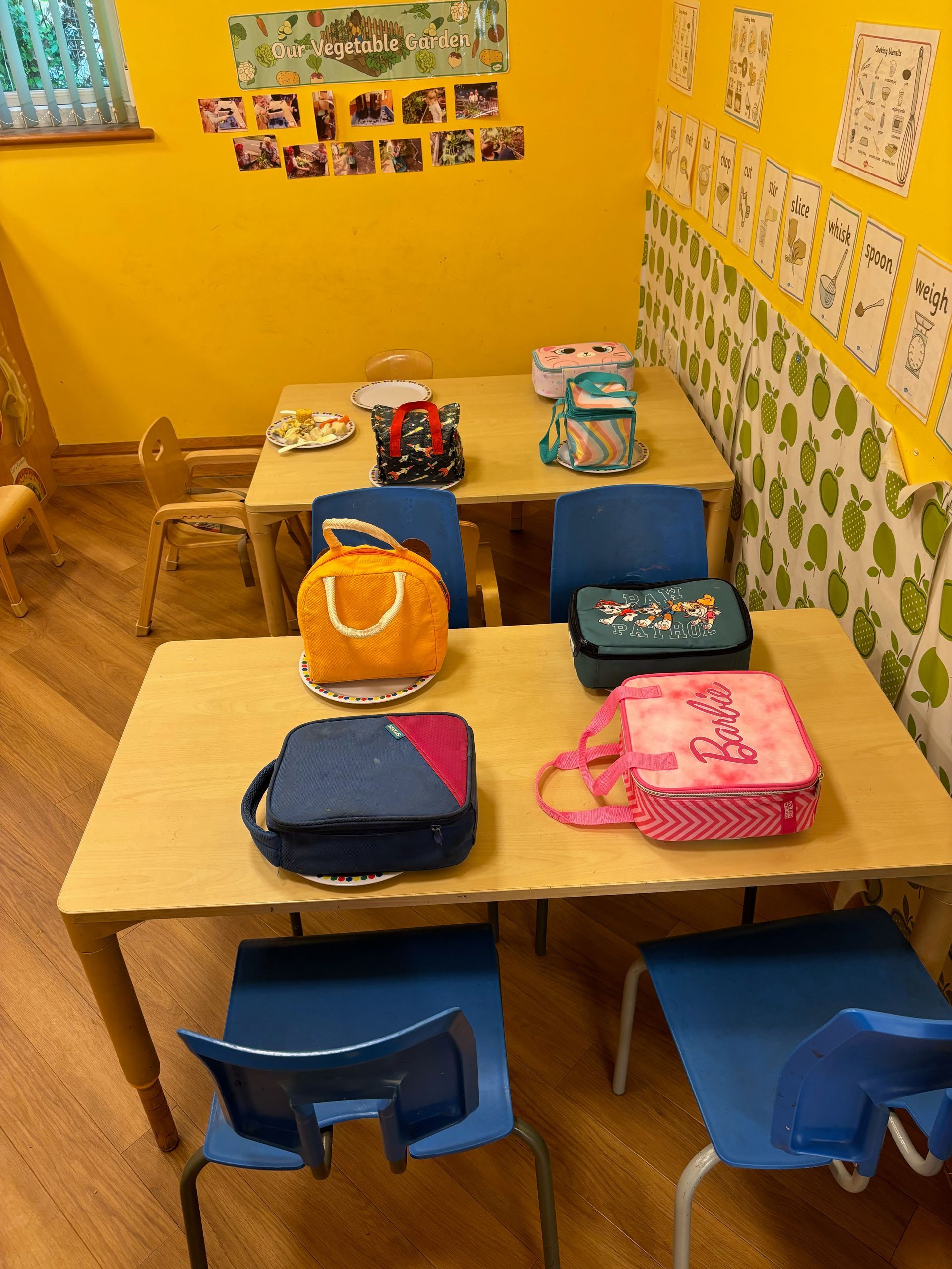 A classroom with tables and chairs and lunch bags on them