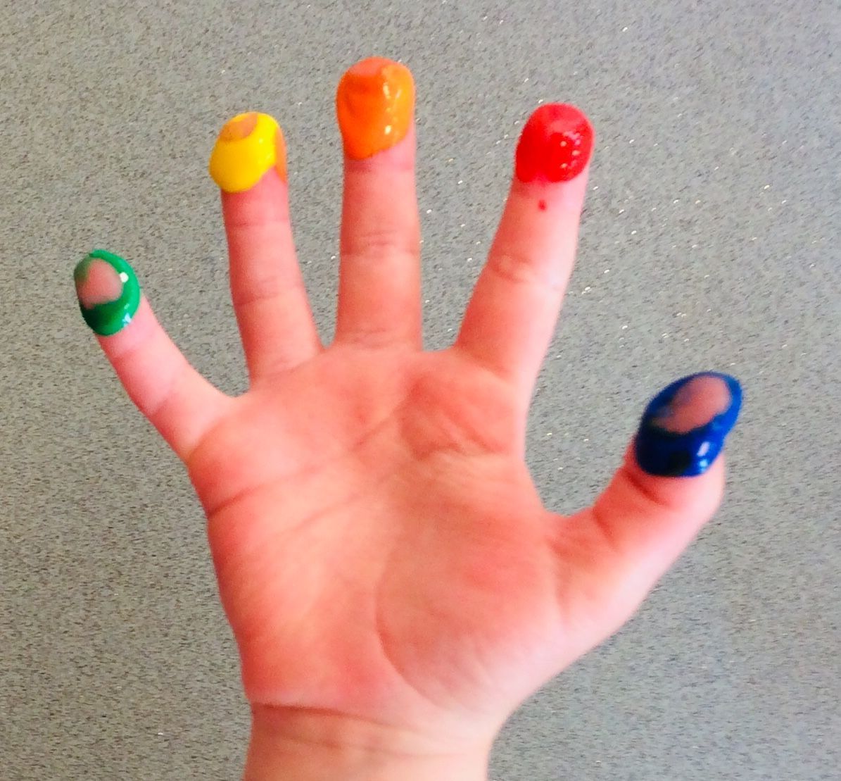 A child 's hand with five fingers painted in different colors