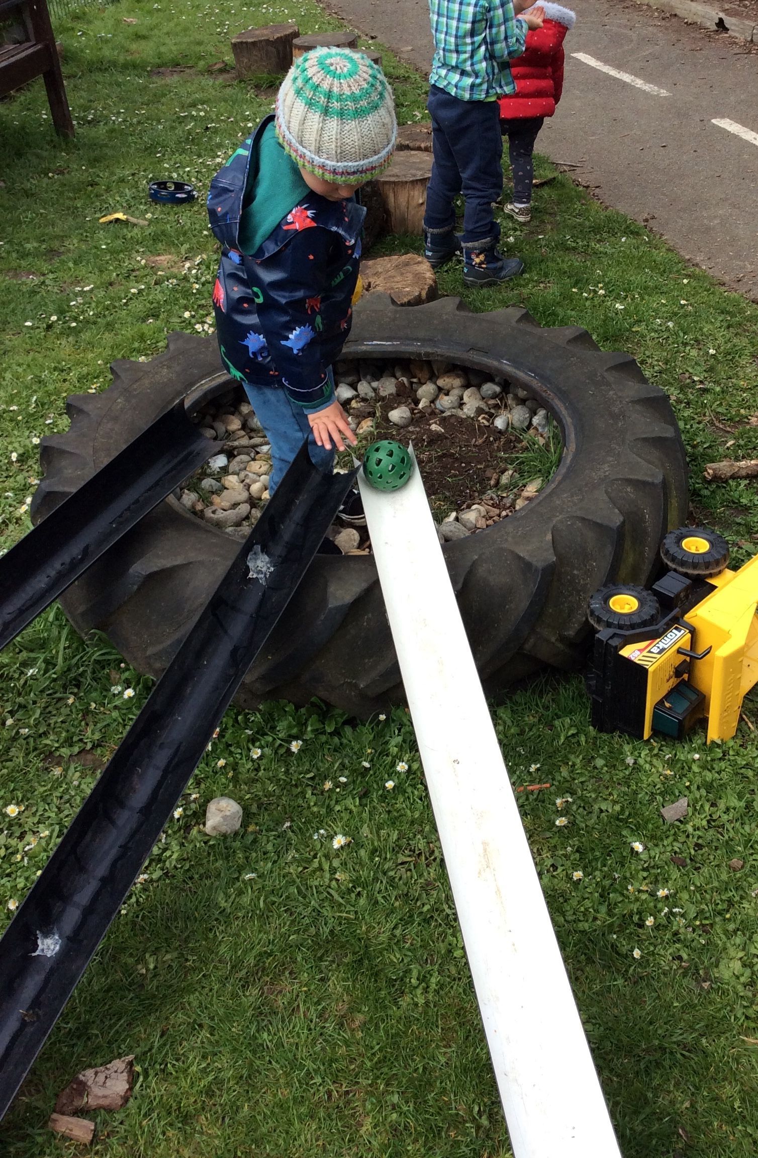 A young boy is playing with a tire and a water slide.