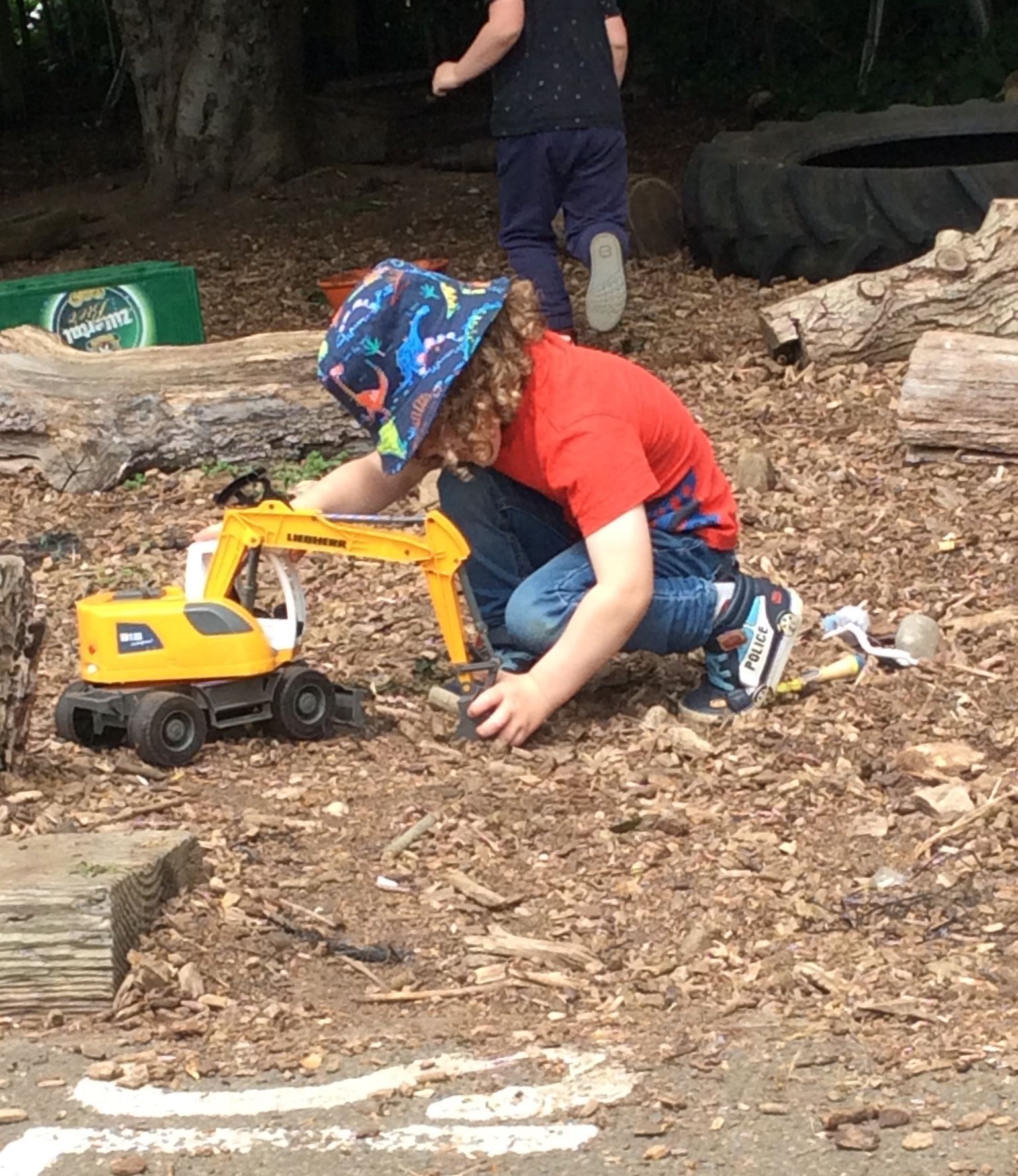 A young boy is playing with a toy excavator in the dirt