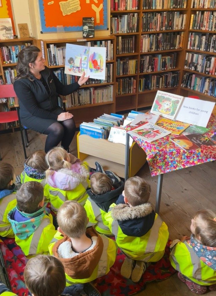 A woman is reading a book to a group of children in a library.