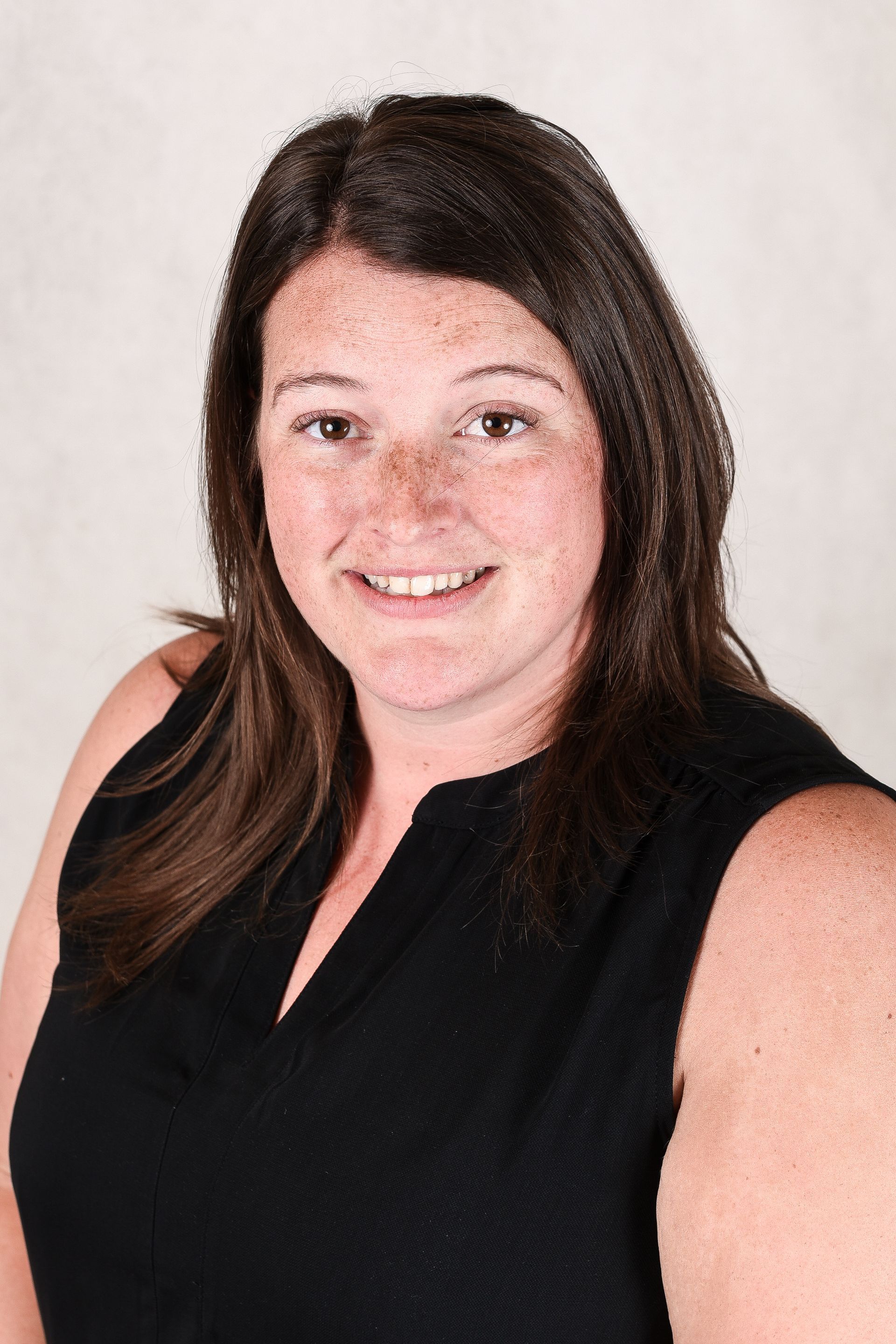 A woman with a name tag on her shirt is smiling for the camera.