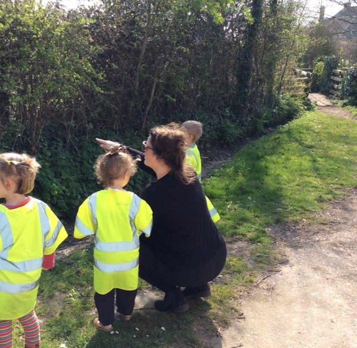 A group of children wearing yellow vests are walking down a dirt path