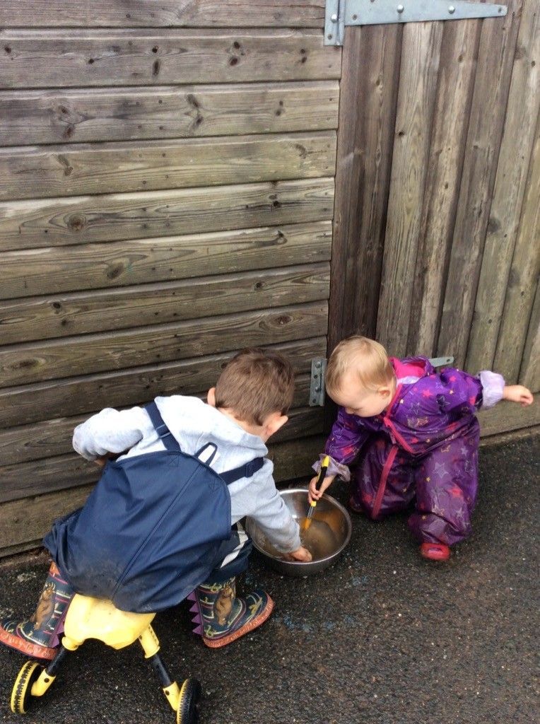 A boy and a girl are playing with a metal bowl.