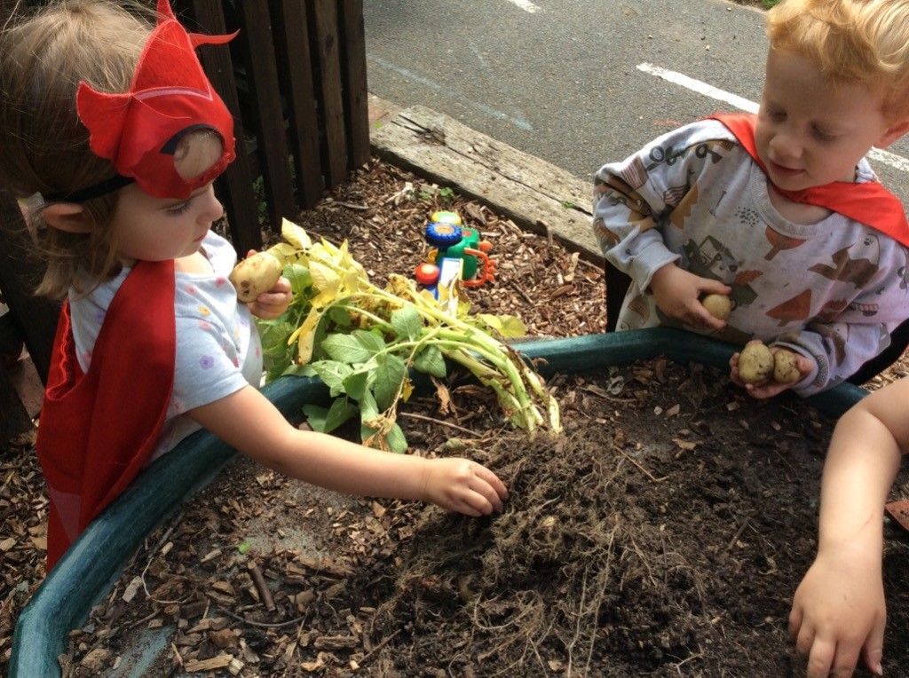 Two children wearing superhero costumes are playing in the dirt.