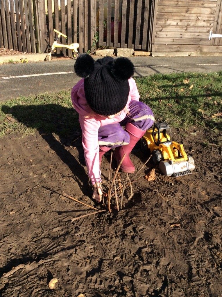 A little girl is playing in the dirt with a toy truck.