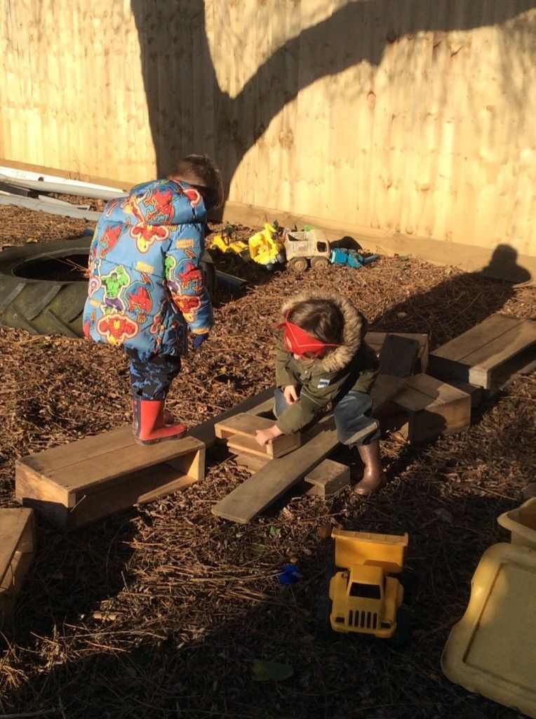 Two children are playing in a wooden playground with toys.
