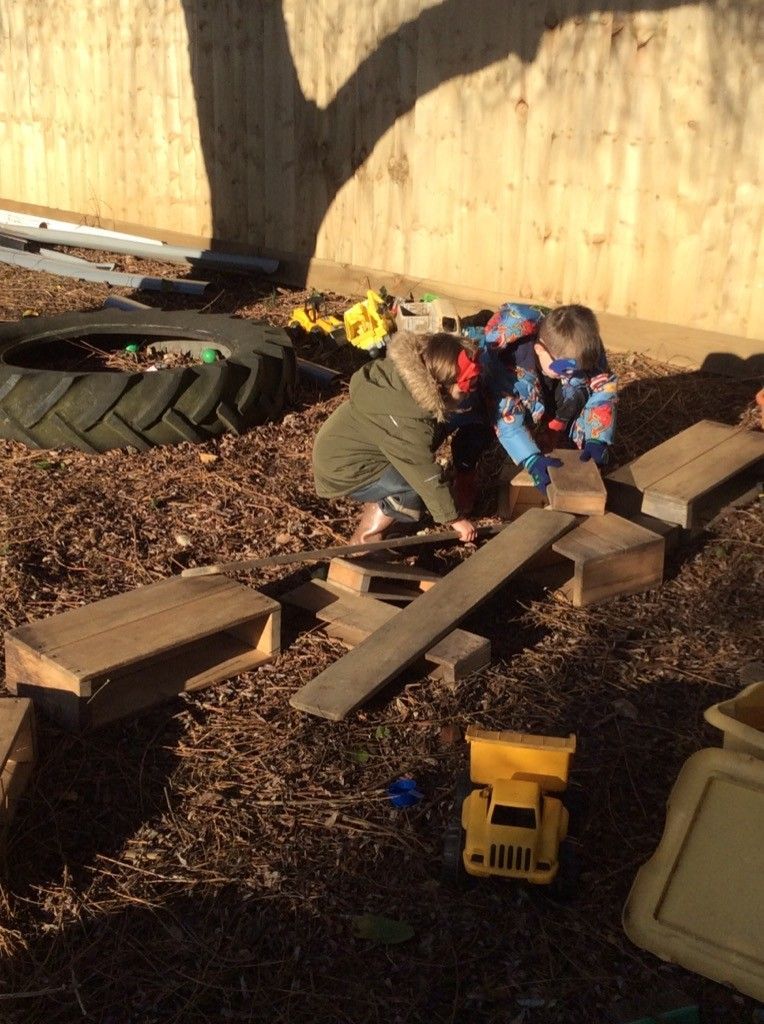 Two children are playing with wooden blocks in a playground.