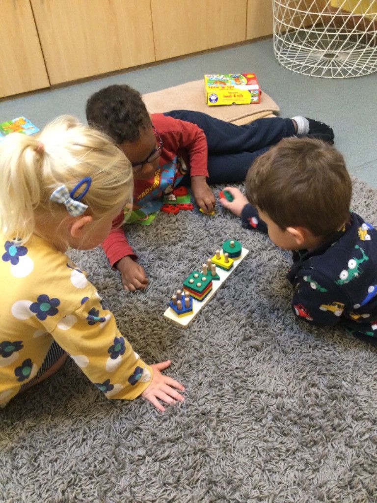 A group of children are playing with toys on the floor.