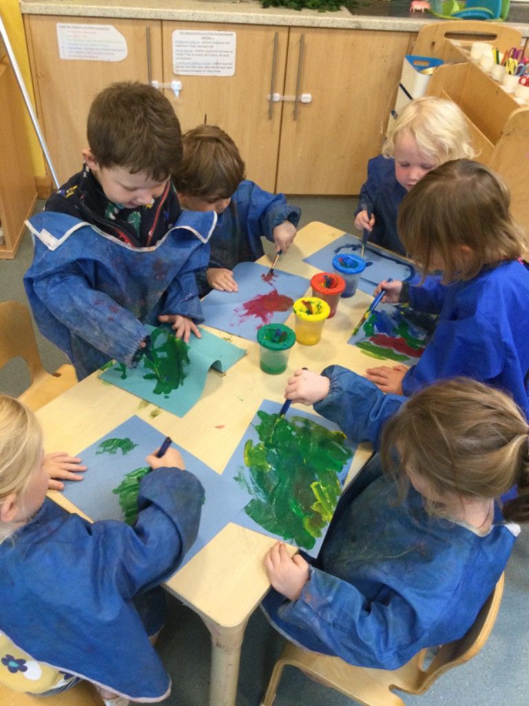 A group of children are sitting at a table painting.