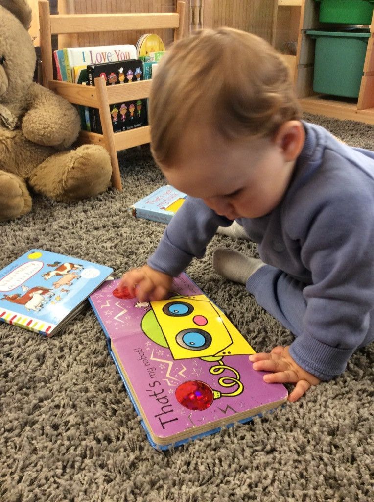 A baby is playing with a book on the floor.