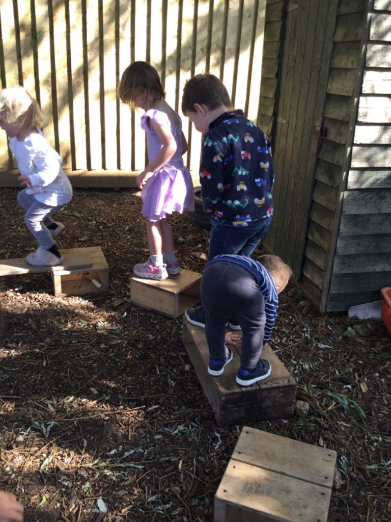 A group of children are playing on wooden blocks.