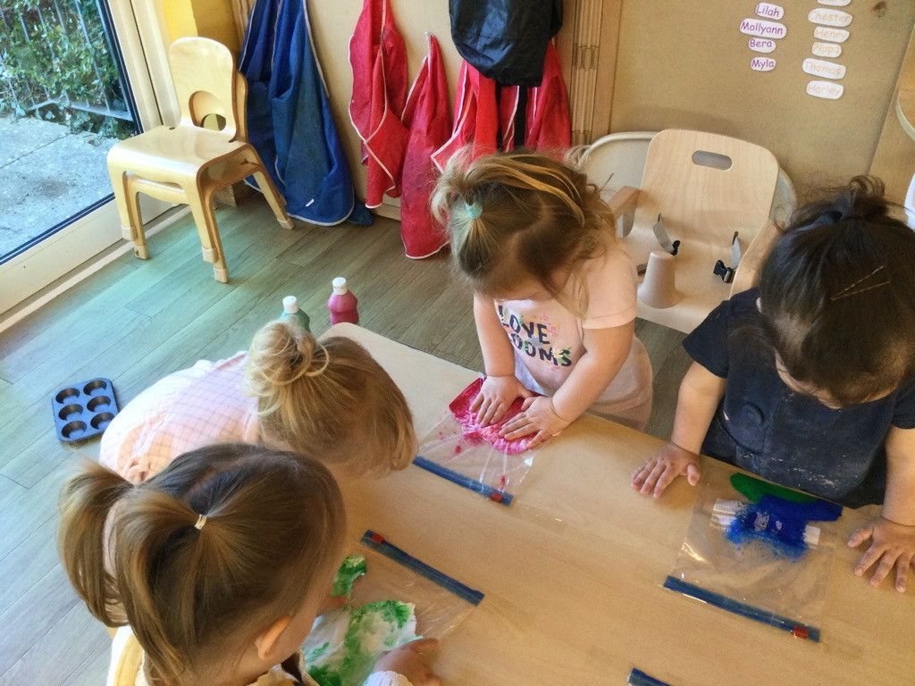 A group of young girls are sitting at a table playing with paint.