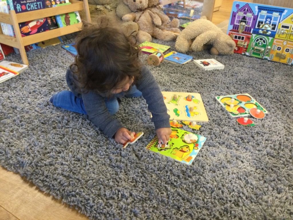 A little girl is playing with a puzzle on the floor.