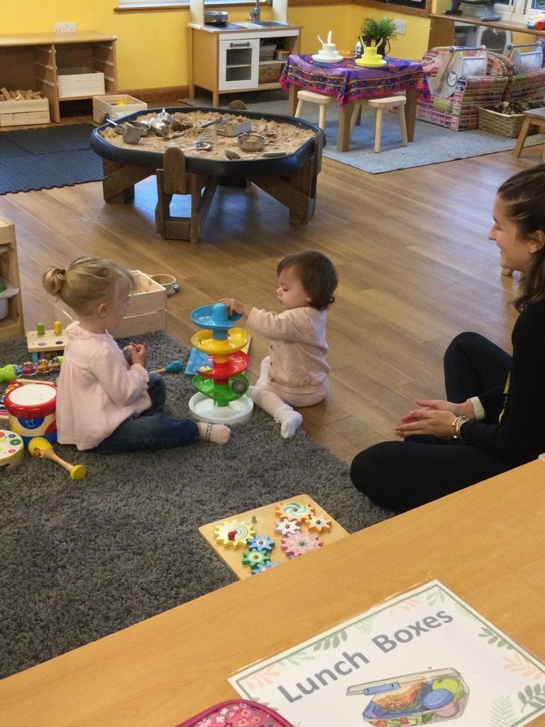A woman is sitting on the floor playing with two children.