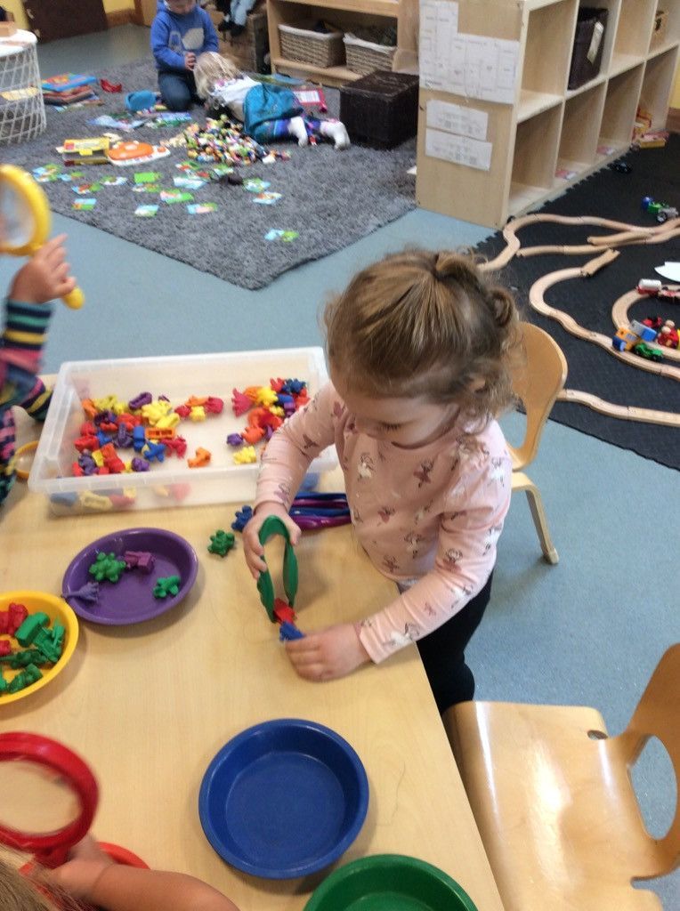 A little girl is sitting at a table playing with toys.