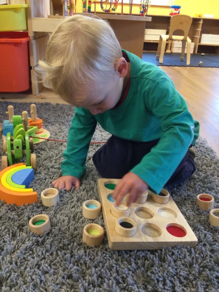 A young boy is playing with a wooden toy on the floor.