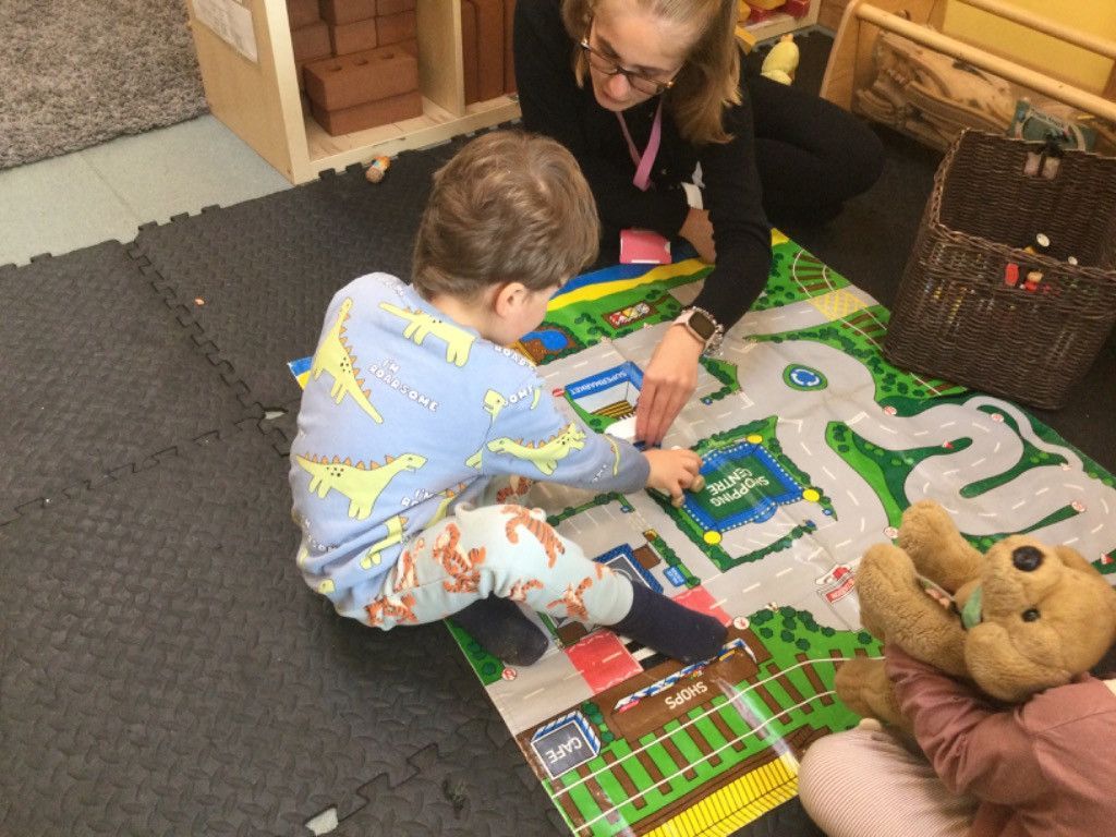A woman is playing with a child on a mat on the floor.