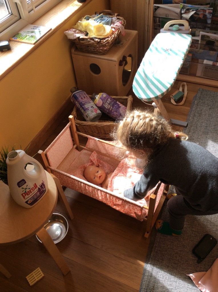 A child is playing with a doll in a crib in a room.