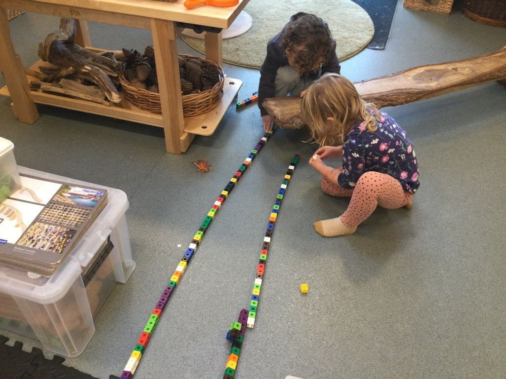 Two children are playing with lego blocks on the floor.