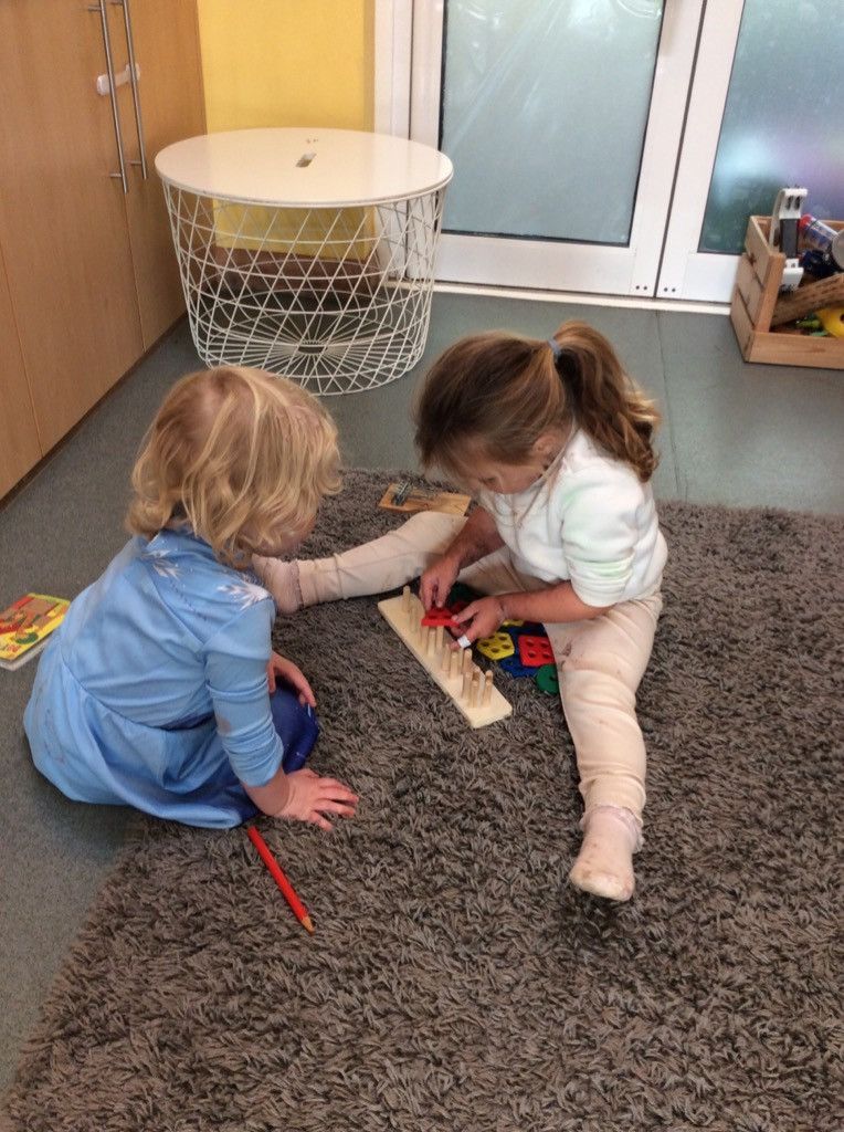 Two little girls are sitting on the floor playing with toys.