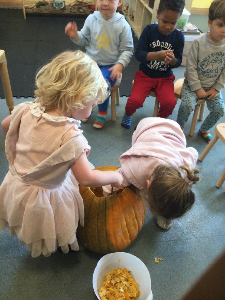 A group of children are sitting around a pumpkin.
